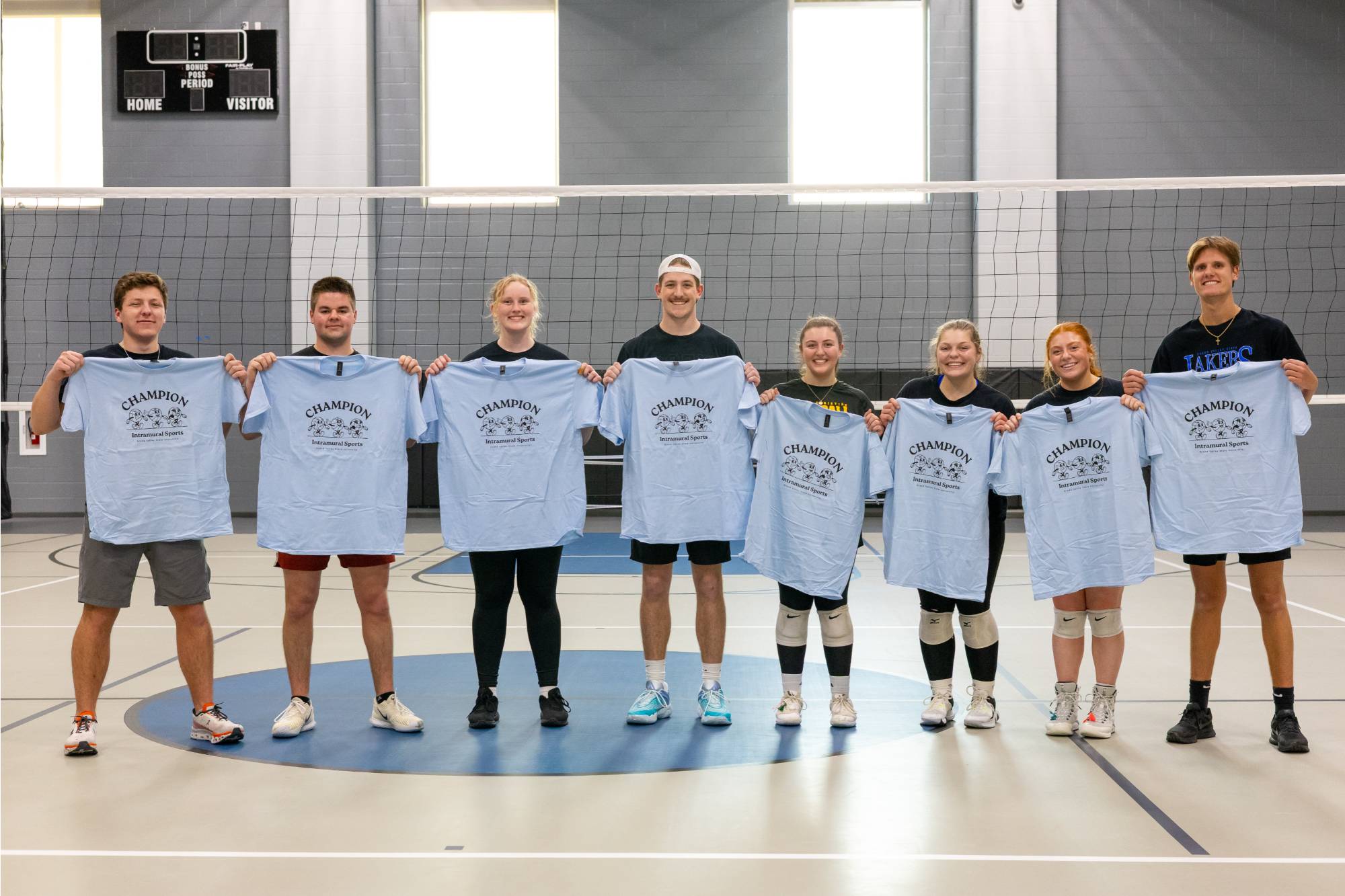 Grand valley students posing with championship t-shirt for winning the white volleyball bracket